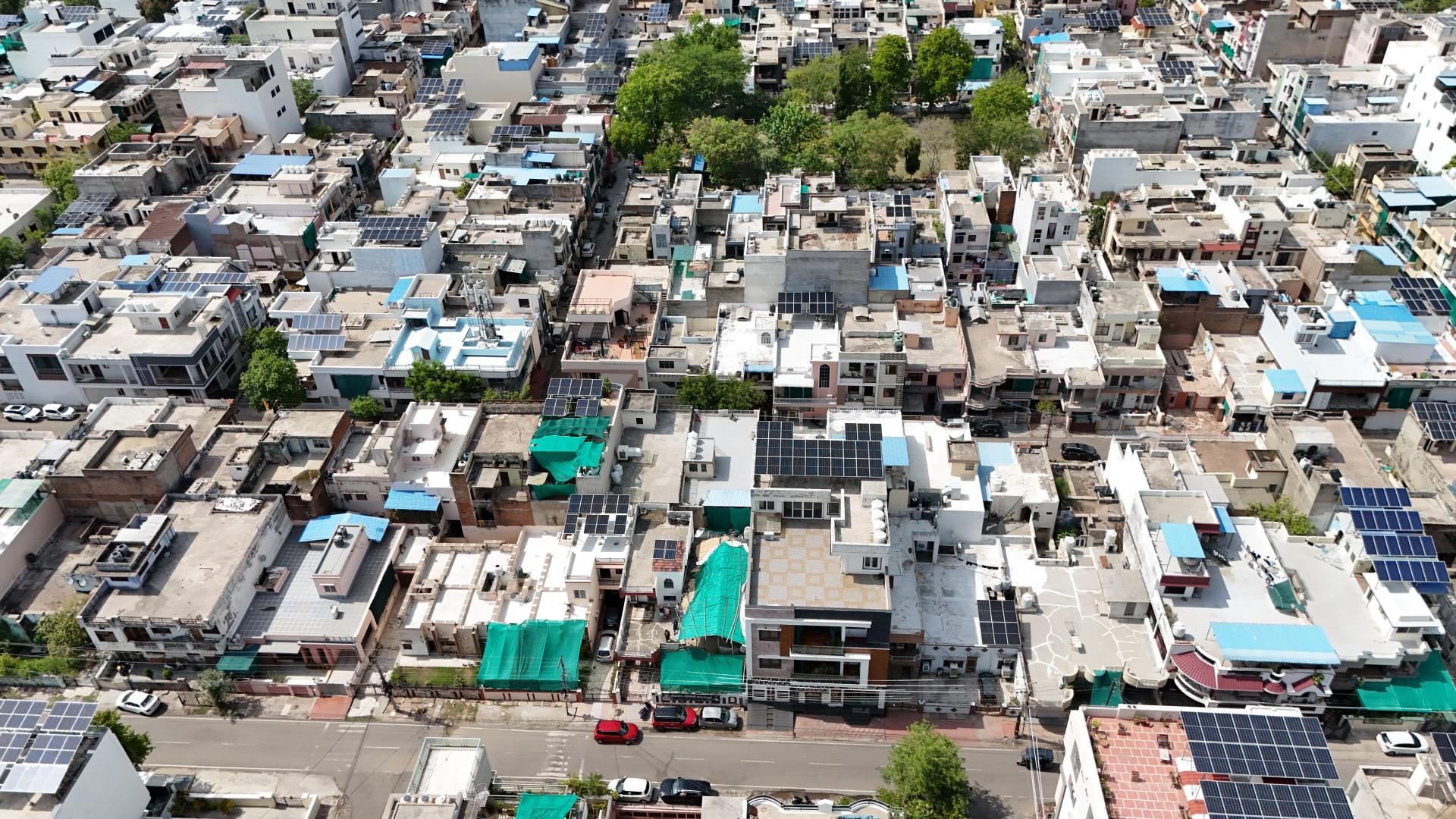 Aerial overview of a Rajasthan neighbourhood with dozens of Renewray solar installations visible on rooftops
